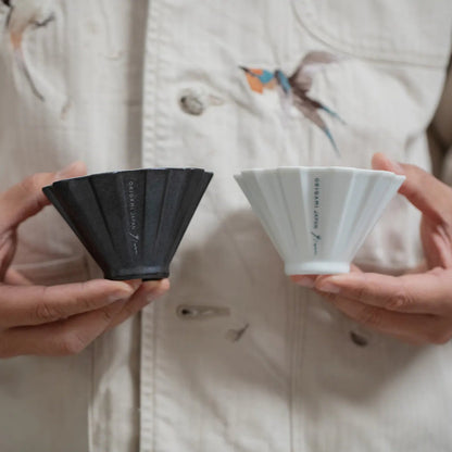 A person holding two Origami Pinn Drippers (Black and White)